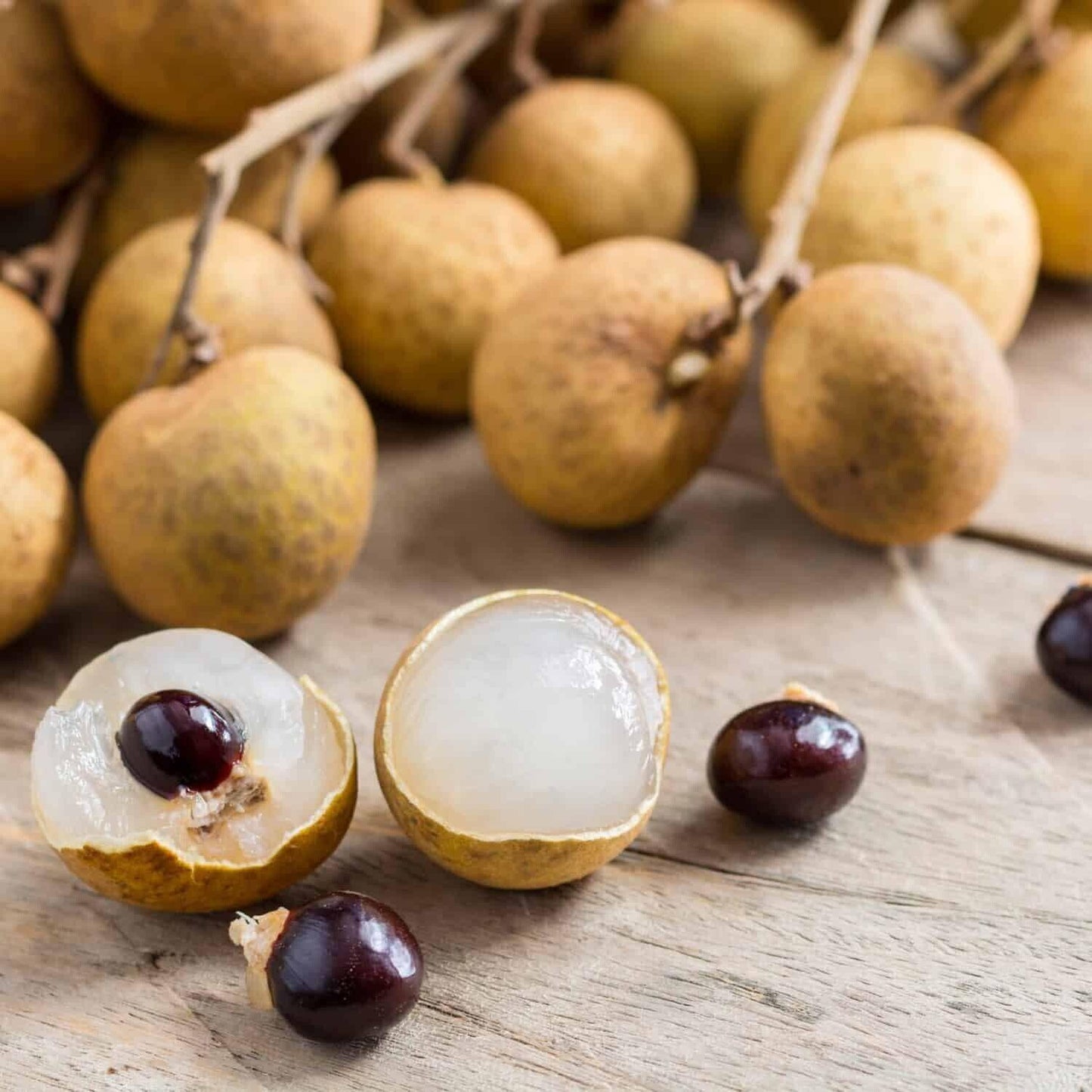 Whole and halved Longan “Dragon Eye” fruit showing translucent flesh and dark seed