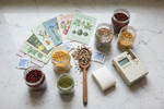 Glass mason jars filled with colorful seeds, seed packets, and silica gel desiccant packets arranged on a marble surface — proper seed storage for maximum longevity