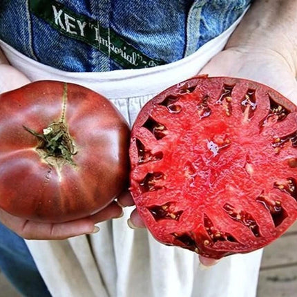 Ripe Cherokee Purple tomato with a cut half showing its interior