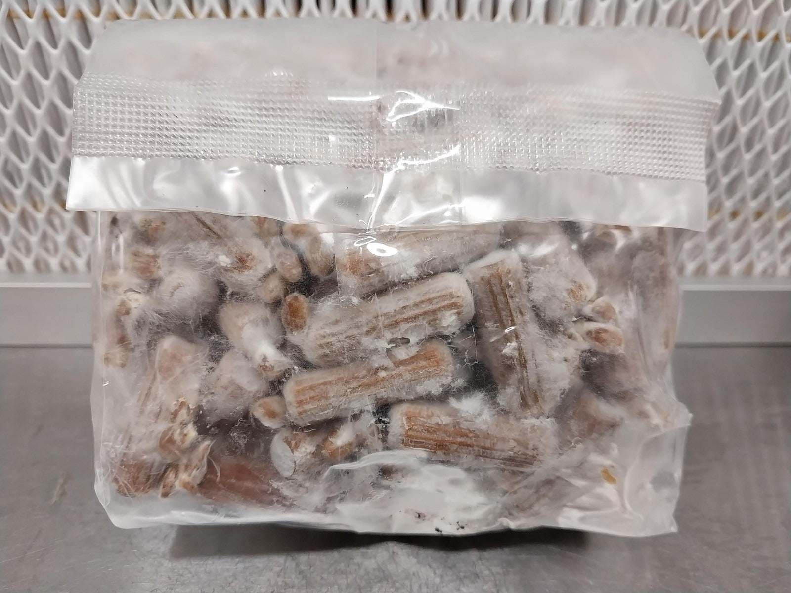 Clear plastic bag filled with small cylindrical objects on a textured surface.