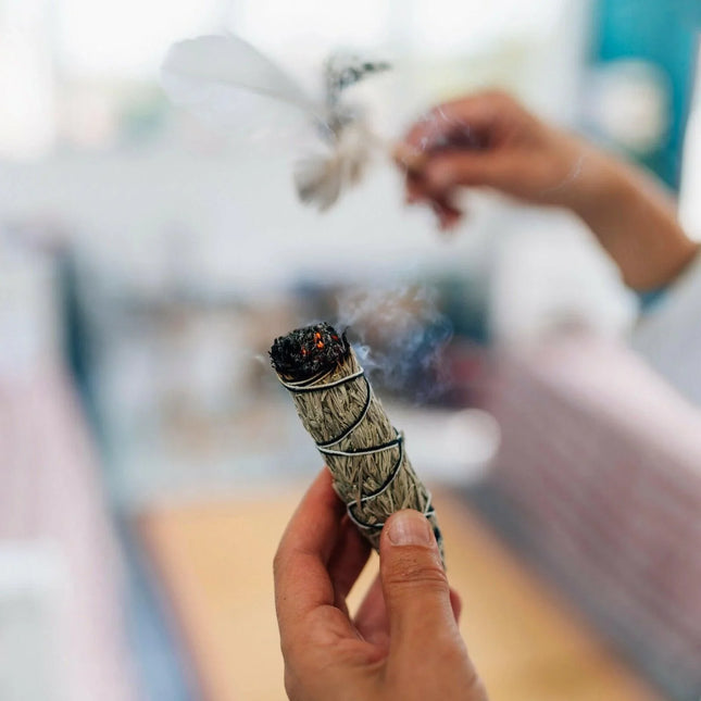Person holding a smoldering sage stick with a blurred background